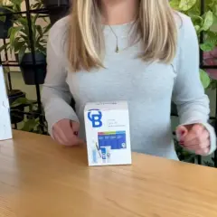 Kit di cura per sonde BlueLab con misuratori pH e conducibilità, su un tavolo di legno con piante sullo sfondo.