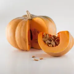 Zucca intera e una fetta con semi, pronti per imparare come piantare i semi di zucca e far crescere un orto autunnale.